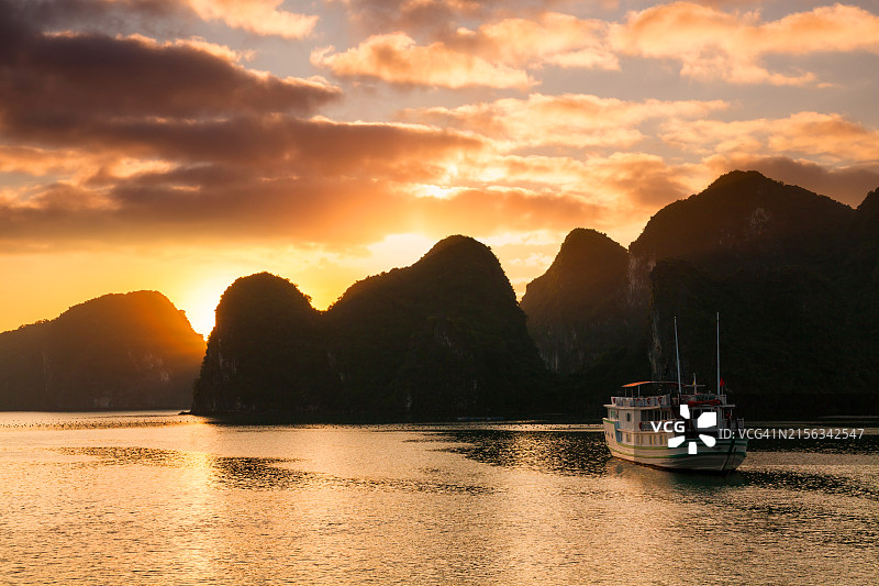 越南下龙湾日落时分的邮轮和岛屿图片素材