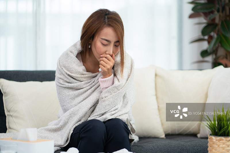 在沙发上感到不适并咳嗽的女人图片素材