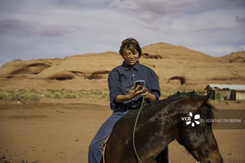 在亚利桑那州北部纪念碑谷部落公园训练的纳瓦霍族少女骑着枣骝马图片素材