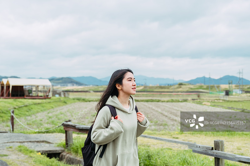 快乐的年轻亚洲女人在日本旅行，沿着田野在户外散步图片素材