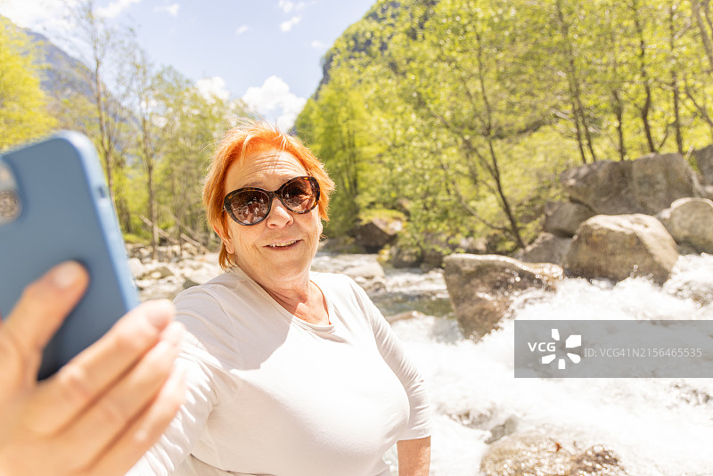 快乐的老年妇女在河边自拍图片素材