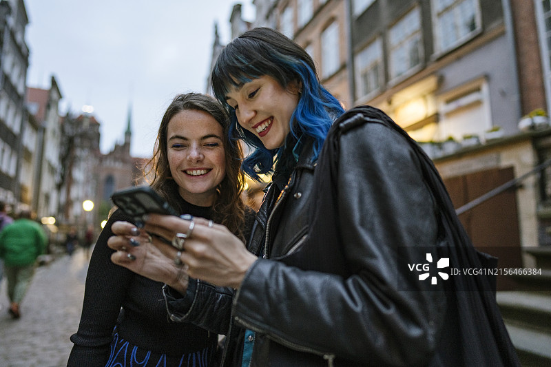两个年轻女人笑着看智能手机图片素材
