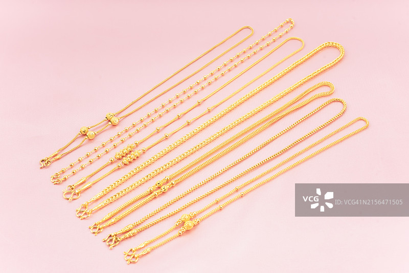 粉色丝绸背景上的金色项链俯视图图片素材