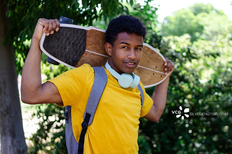 年轻男子在公园里课后拿着长板图片素材