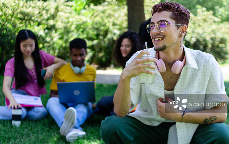 年轻男人在公园与朋友学习时享用奶昔图片素材
