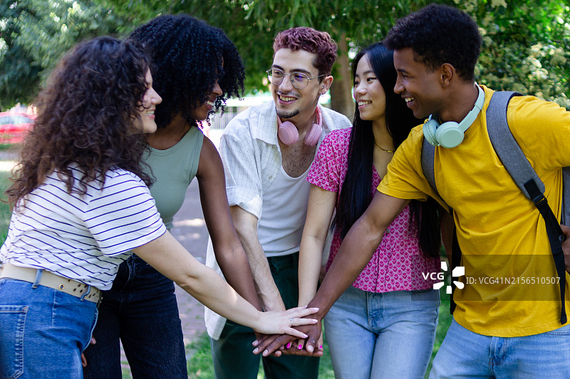 五个快乐而多元化的学生在公园里手牵手图片素材
