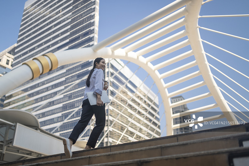 职业女性攀登阶梯：企业城市景观背景。适用于营销、网站设计、商务演示和促销材料的高分辨率库存照片。立即在Adobe Stock上下载。图片素材