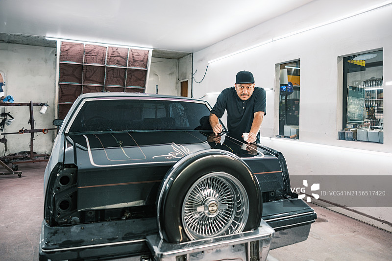 中年拉丁裔男子在汽车车身喷漆间工作图片素材
