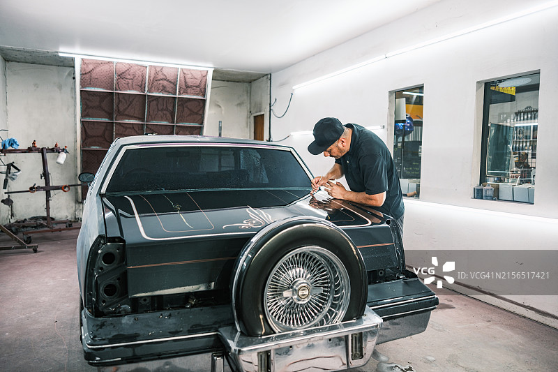 中年拉丁裔男子在汽车车身喷漆间工作图片素材