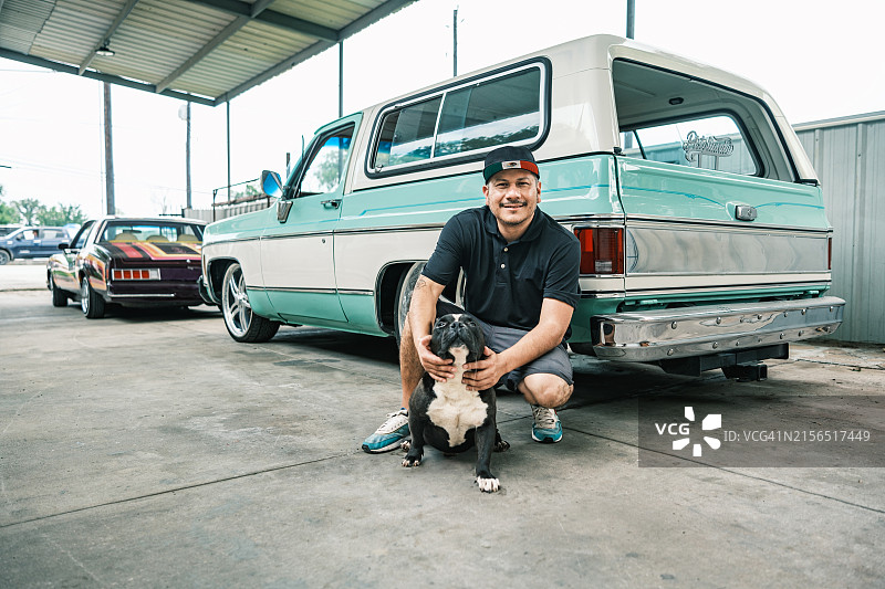 中年拉丁裔男性企业主和他的狗在汽车车身喷漆店图片素材