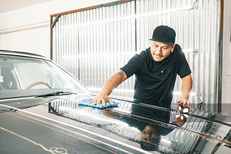 中年拉丁裔男子在汽车车身喷漆间工作图片素材