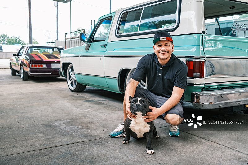 中年拉丁裔男性企业主和他的狗在汽车车身喷漆店图片素材