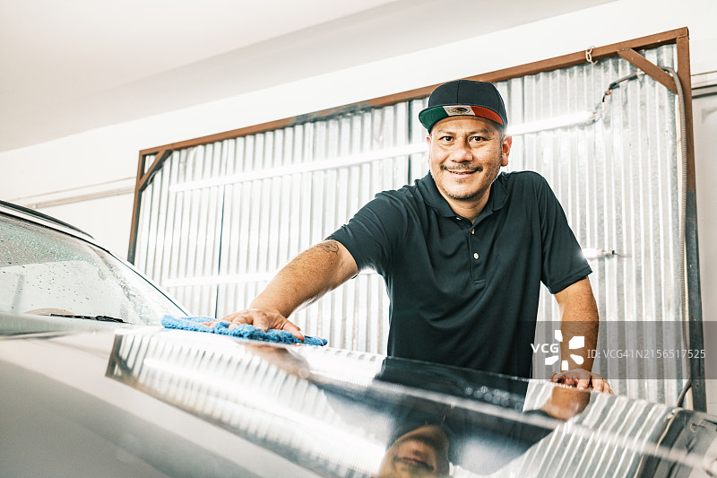 中年拉丁裔男子在汽车车身喷漆间工作图片素材