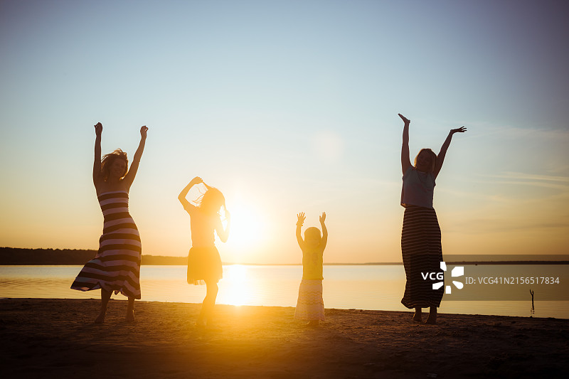 日落时分站在海滩上的朋友剪影图片素材