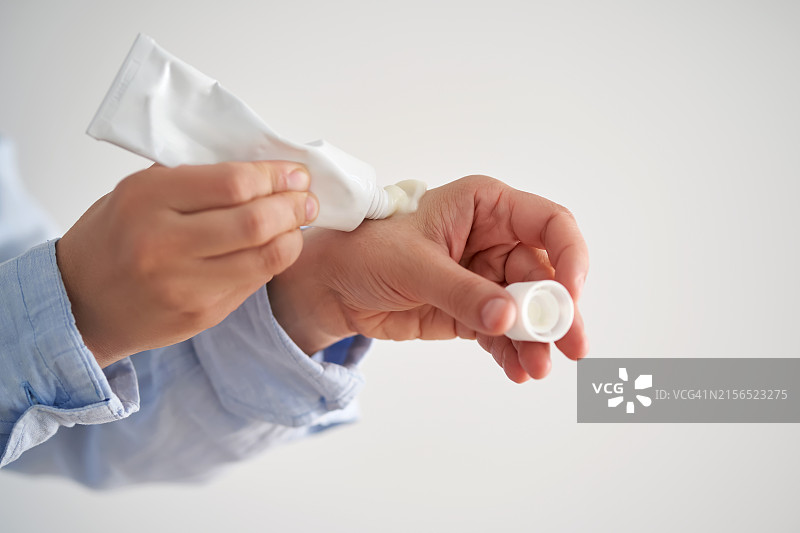 女人拿着保湿霜，白色背景，手部特写图片素材