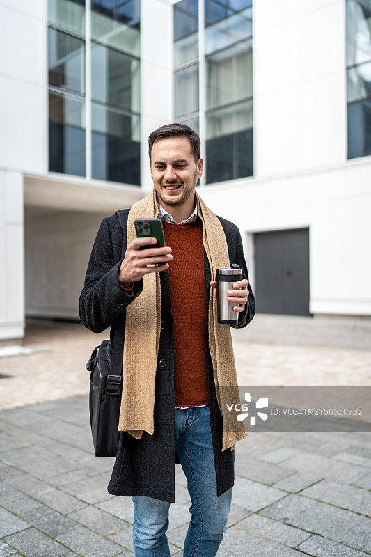 使用智能手机喝咖啡的年轻商人图片素材