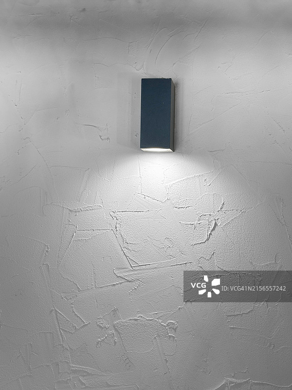 带有直线的聚光灯照亮了带有乡村饰面的白色墙壁的一部分，具有工业气息的极简装饰图片素材