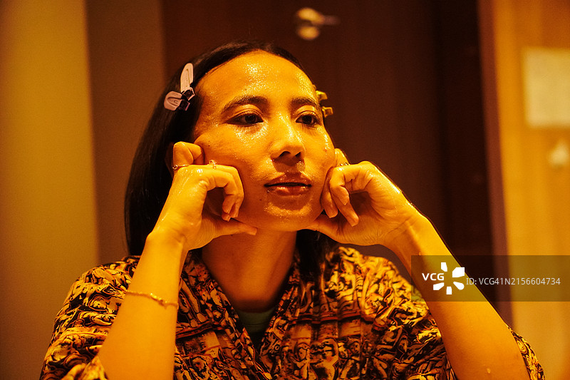 年轻的亚洲女人在浴室镜子里检查皮肤图片素材