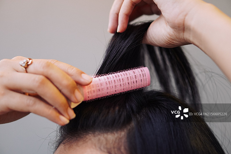 用粉色卷发器卷刘海的女人图片素材