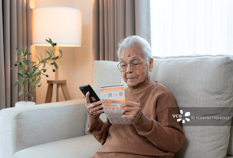 年长的女人用手机阅读说明书图片素材