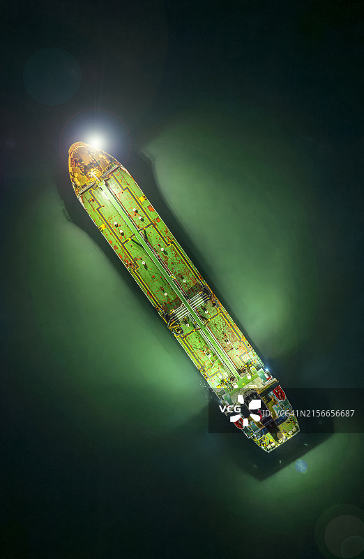 航拍：绿色油轮（橙色船头）停靠在海边海湾，等待运往炼油厂图片素材