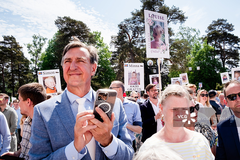 在芬兰奥兰群岛玛丽港奥兰学院毕业典礼上，手持标语和手机庆祝传统北欧节日的友人们图片素材