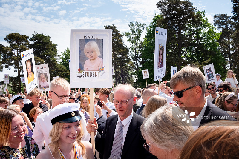 在芬兰奥兰群岛玛丽港奥兰学院毕业典礼上，手持标语和手机庆祝传统北欧节日的友人们图片素材