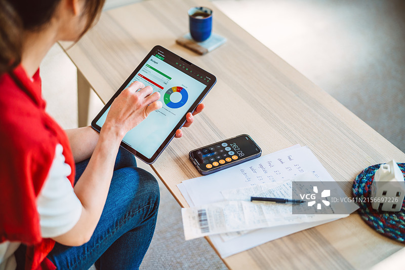 年轻的亚洲女性在家使用AI金融应用程序管理家庭预算图片素材