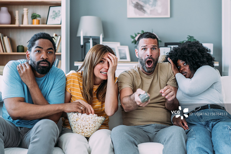 朋友们在家看恐怖电影，感到害怕图片素材