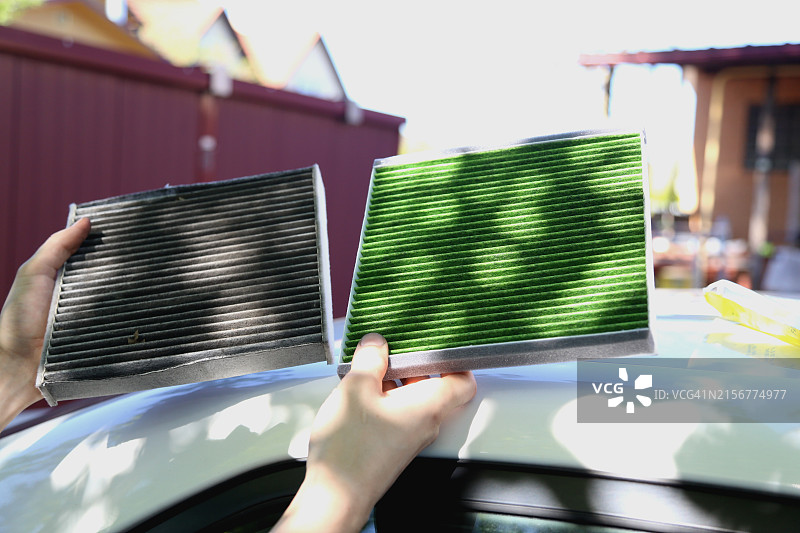 汽车修理工在家修理汽车并更换空气净化器，手持旧汽车滤清器和新的环保滤清器图片素材