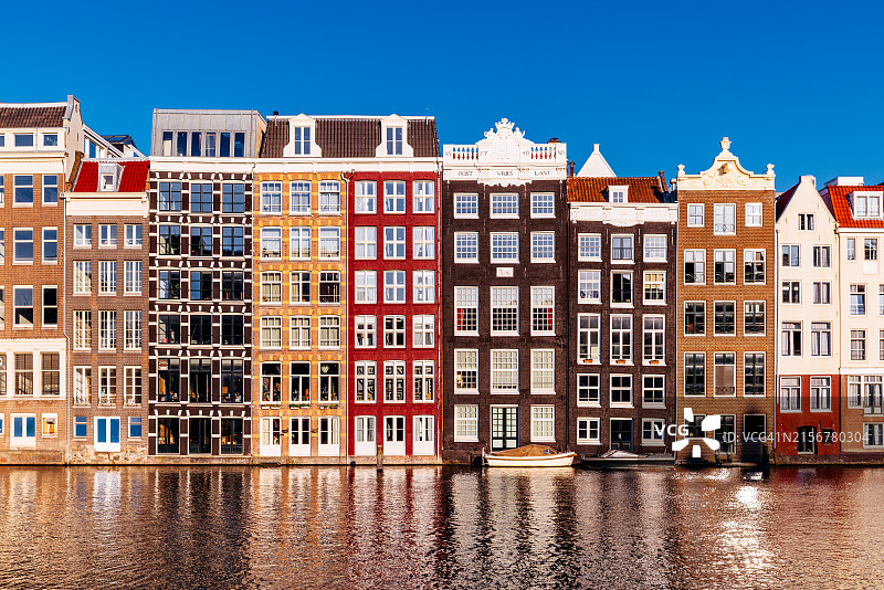 阳光明媚的日子里，阿姆斯特丹丹拉克运河沿岸的传统荷兰房屋图片素材