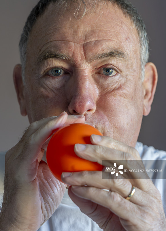 吹橙色气球的年长男人图片素材
