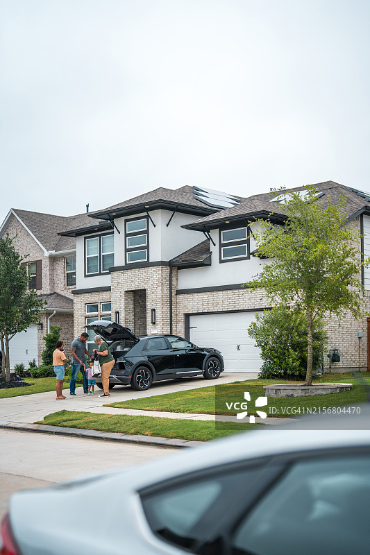 环保住宅户外，多民族家庭与电动汽车图片素材