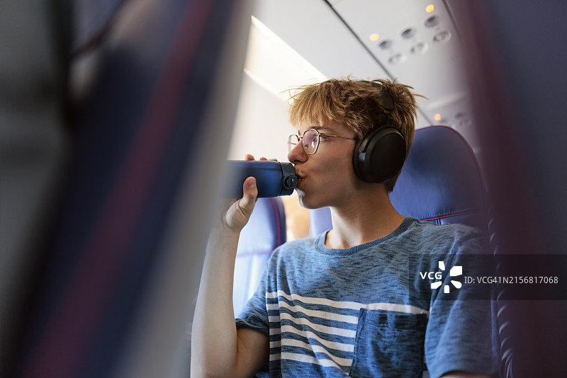 乘飞机旅行时喝水的青少年男孩图片素材