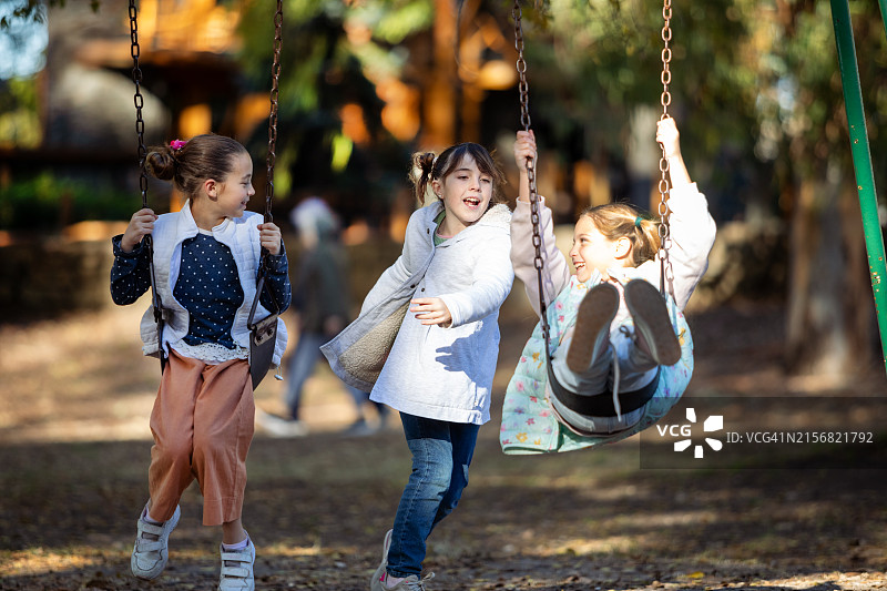 在游乐场的吊床上快乐的小女孩们图片素材