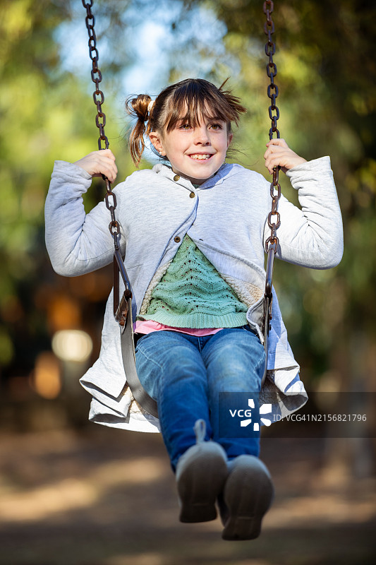 在游乐场吊床上玩耍的快乐小女孩图片素材