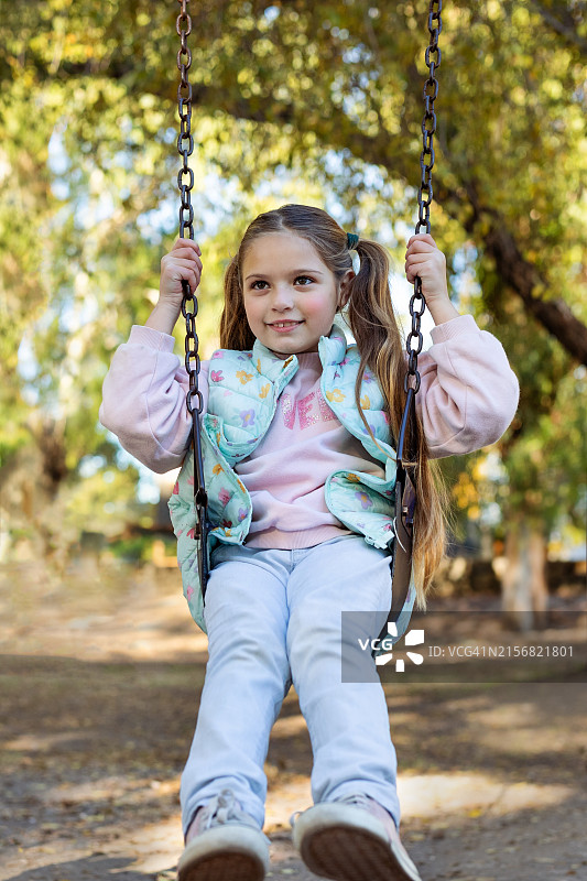 在游乐场吊床上玩耍的快乐小女孩图片素材