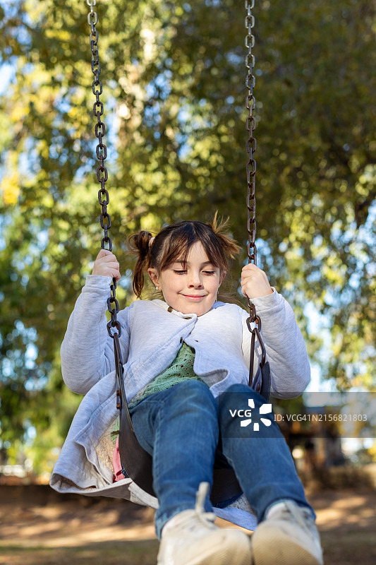 在游乐场吊床上玩耍的快乐小女孩图片素材