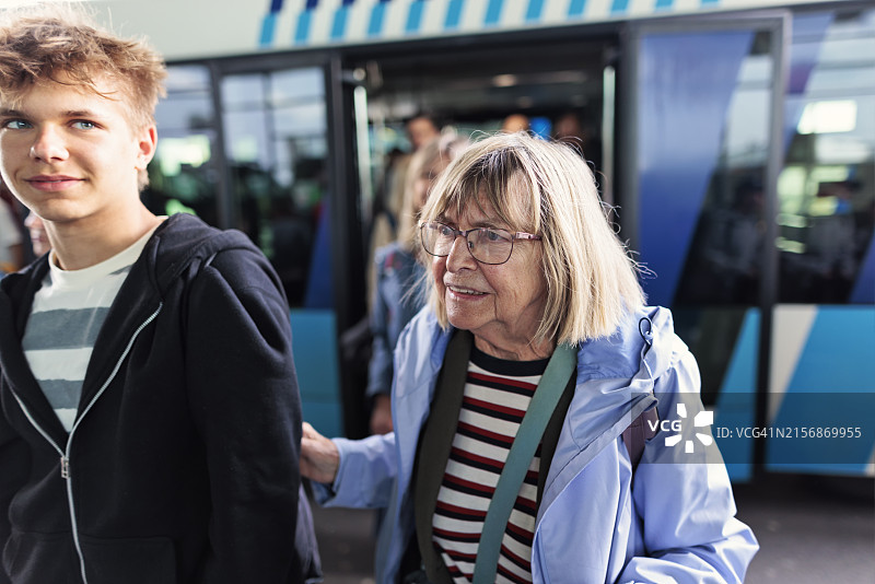 年长的女人和十几岁的孙子从机场的班车上走下来图片素材