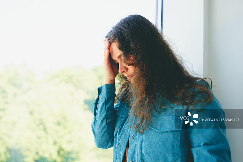 靠窗沉思，手扶头部的女子图片素材