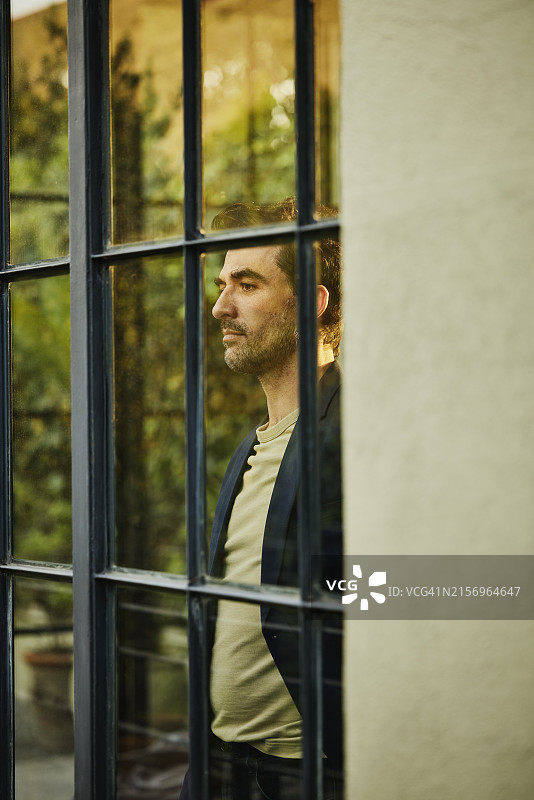 男人在豪华精品酒店的窗户向外看（中景）图片素材