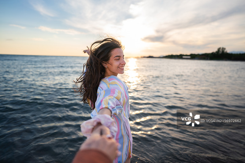 快乐的女人和她的男朋友在海滩上跑步图片素材