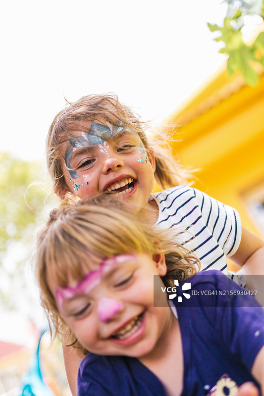 小女孩们玩着彩色面部彩绘，享受户外乐趣图片素材