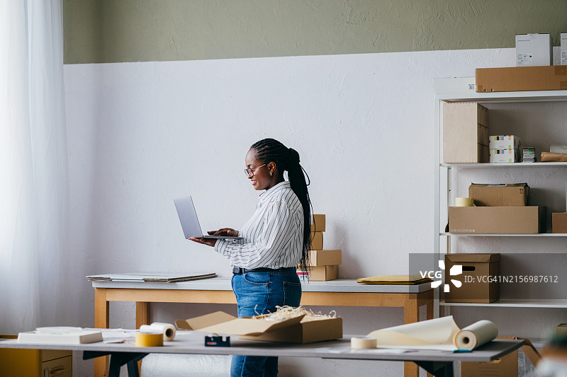 在现代办公室使用笔记本电脑的年轻女人图片素材