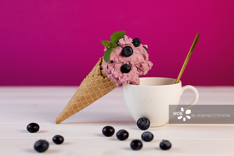 华夫饼冰淇淋和白色空杯与金勺：浆果甜点组合，紫色背景图片素材