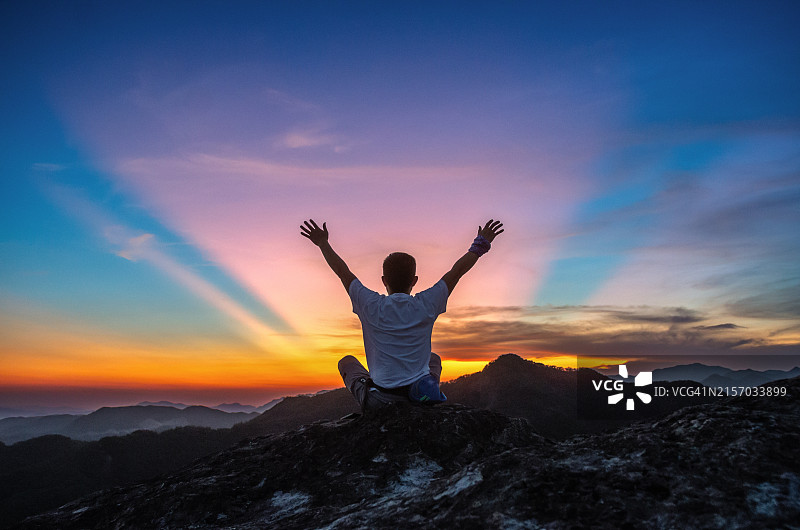 坐在山顶上向日落挥手图片素材