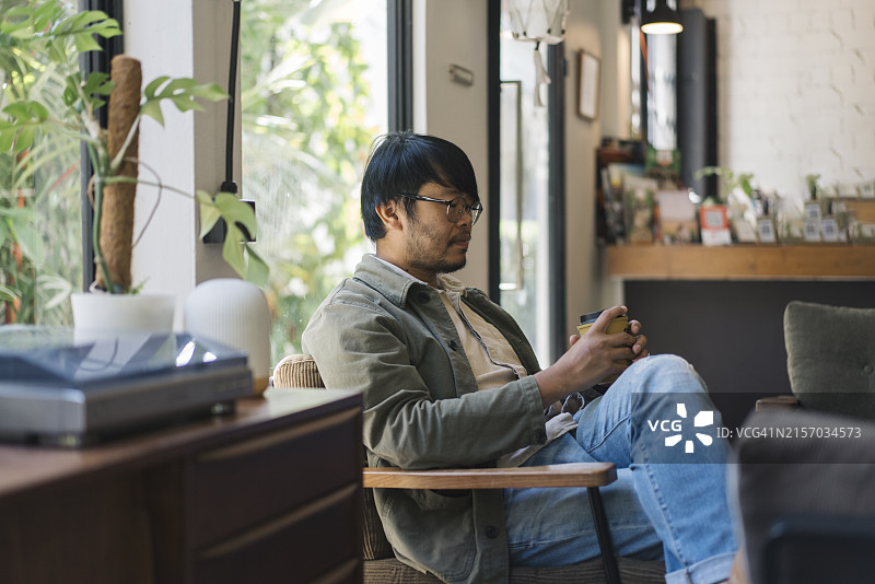 居家办公时，男子放松伸展，笔记本电脑放在腿上，提倡健康图片素材