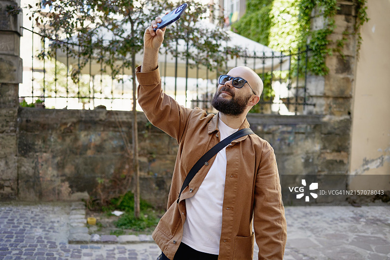 男人用手机从不同角度拍摄城市照片，街头摄影图片素材