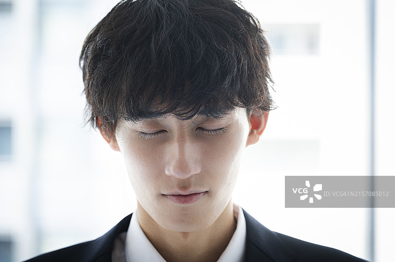 闭眼俯视的日本男学生图片素材