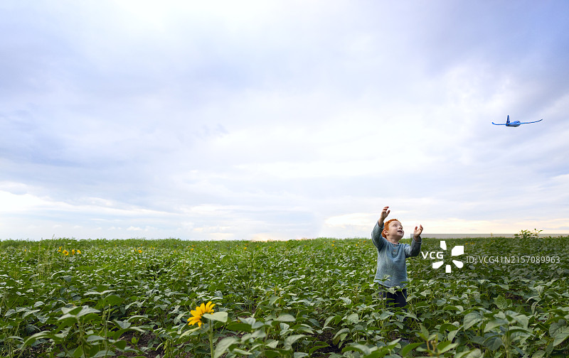 微笑男孩在田野里玩玩具飞机图片素材